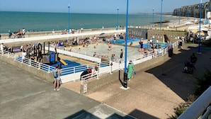 A beachside promenade with a swimming pool, benches, and a small play area. - The lighthouse facing the sea (Saint-Valery-en-Caux)
