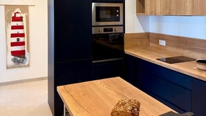 A modern kitchen with dark cabinetry, a wooden countertop, and a stainless steel oven. - The lighthouse facing the sea (Saint-Valery-en-Caux)
