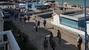 A coastal promenade with a clear view of the sea, a parking area, and a small building with a blue roof. - The lighthouse facing the sea (Saint-Valery-en-Caux)