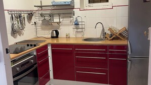Una cocina compacta con horno empotrado, lavamanos y refrigerador.