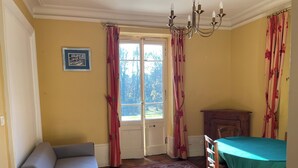 Una habitación con un sofá, una mesa con mantel verde, un armario de madera y una alfombra estampada.