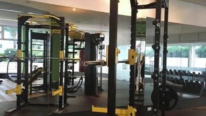 Uma academia com diversos equipamentos de exercícios, incluindo suporte para agachamento e bancos de peso.
