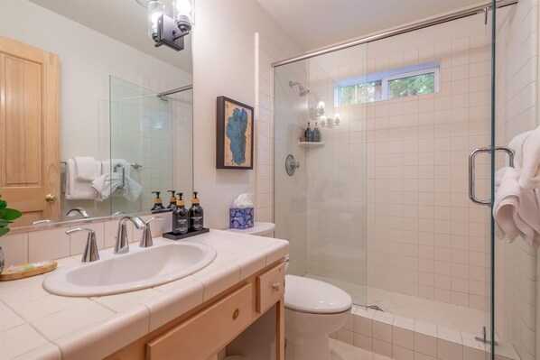 A modern bathroom with a glass-enclosed shower, a large mirror, and a vanity with a sink and towel rack. - Tahoe Pines Beach Retreat 3 Bedroom Home (Homewood)