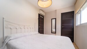 Un dormitorio con cama, luz en el techo, armario y ventana.
