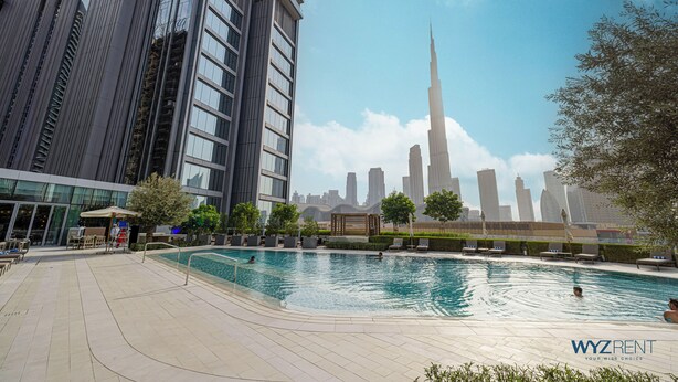 A swimming pool area with lounge chairs and a view of the Burj Khalifa. - WYZ RENT|2BR Vida Dubai Mall Direct Mall Access (Dubai)