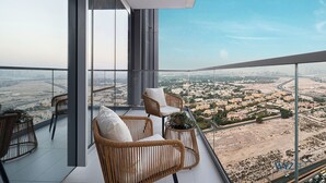 A balcony with wicker furniture and a view of a cityscape. - WYZ RENT|2BR Vida Dubai Mall Direct Mall Access (Dubai)