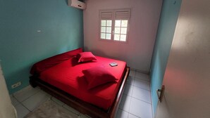 A small, single-bed room with a red bedspread, a window with blinds, and a ceiling fan. - Les terrasses de Maëlle II - Pretty villa with pool and sea view in Rivière-Salée (Rivière-Salée)