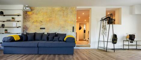 Un salon moderne avec un canapé bleu foncé, un plancher en bois et un mur à texture.