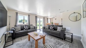 A spacious living room with two grey sofas, a wooden coffee table, and a patterned rug. - Raven Lodge (Brigg)