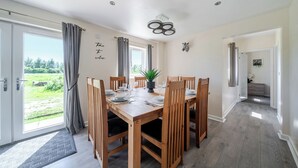 A dining area with a wooden table, chairs, and a potted plant. - Raven Lodge (Brigg)