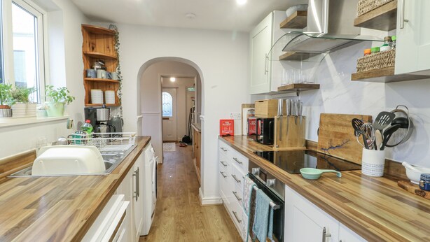 A modern kitchen with wooden countertops, white cabinets, and a central island. - Hafan Hapus (Beaumaris)