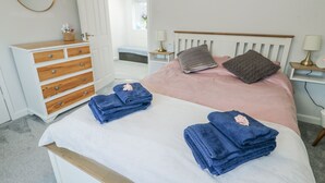 A bedroom with a bed, a dresser, a nightstand, and a lamp. - Hafan Hapus (Beaumaris)