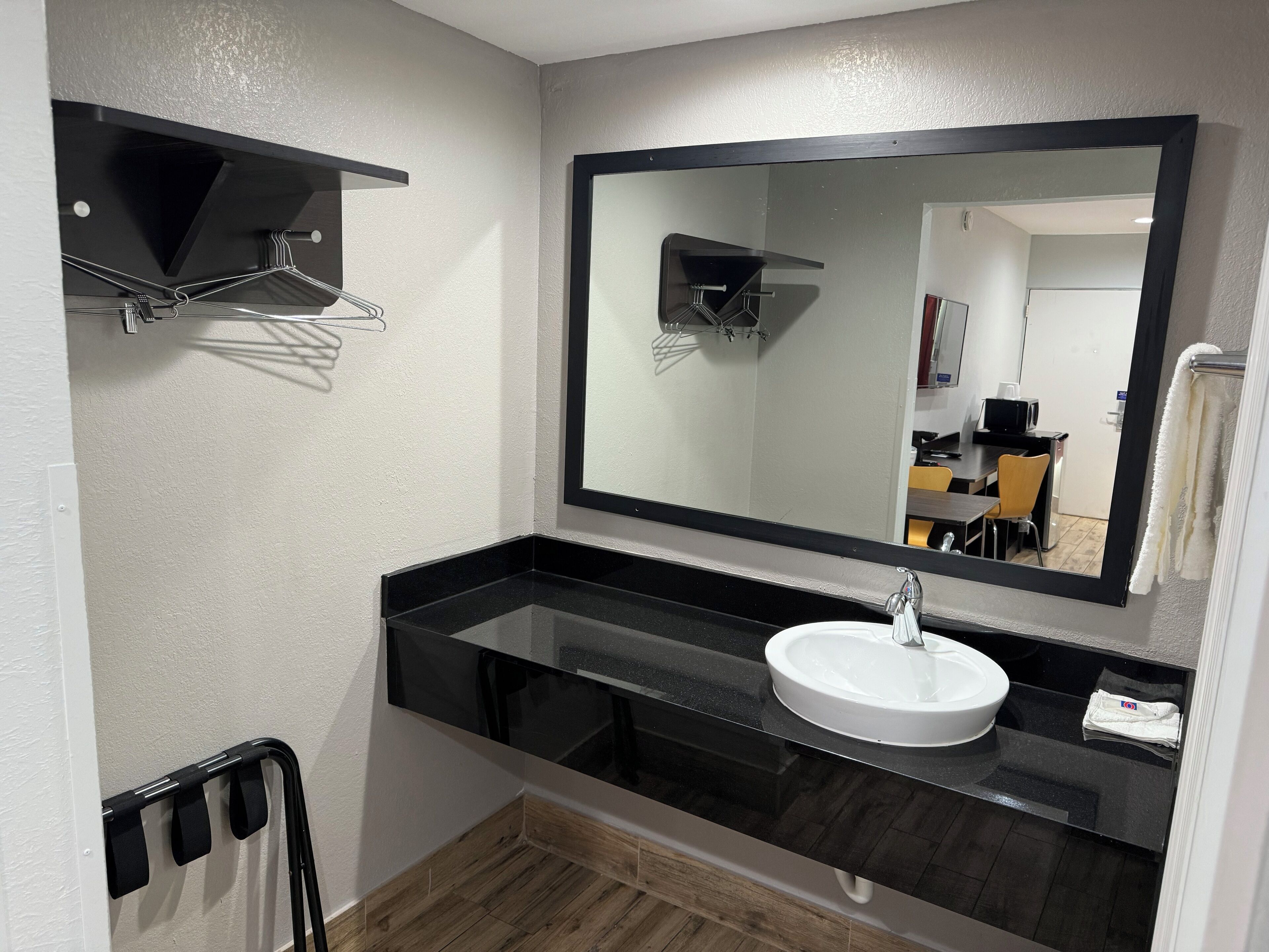 A modern bathroom with a black countertop, white sink, and a large mirror.