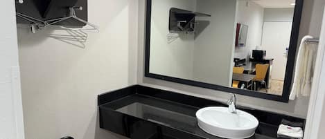 A modern bathroom with a black countertop, white sink, and a large mirror.