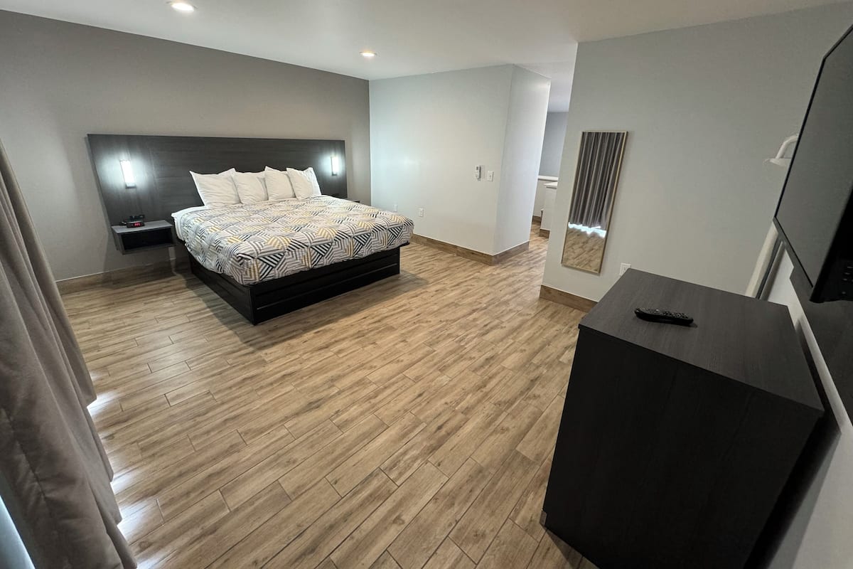 Un dormitorio moderno con cama, mesitas de noche, televisor y espejo.