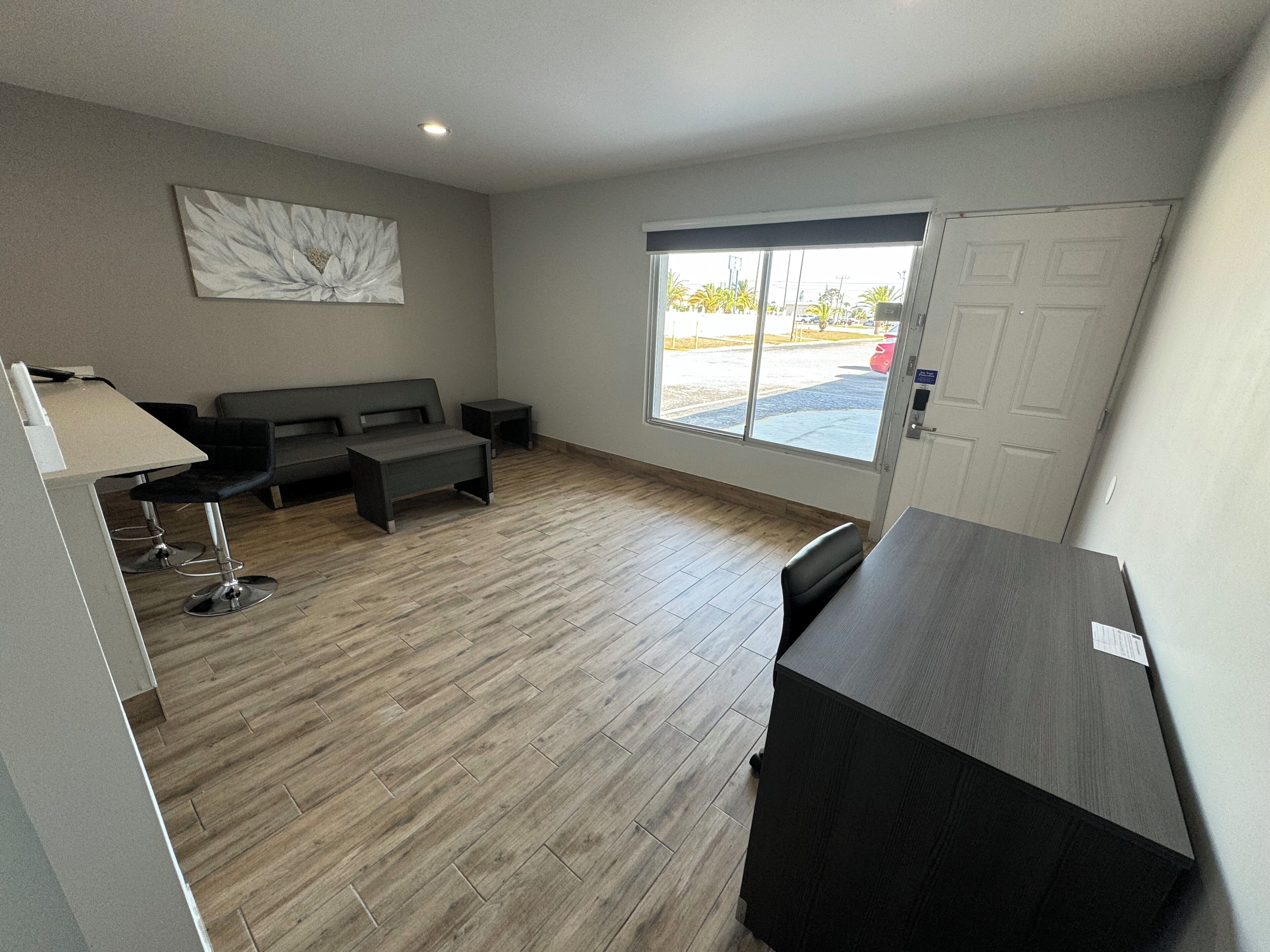 A modern room with a wooden floor, a sofa, a small table, and a desk.