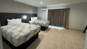 A hotel room with two beds, a dark headboard, a large window with curtains, and a tiled floor. - Englewood Inn & Suites (Englewood)