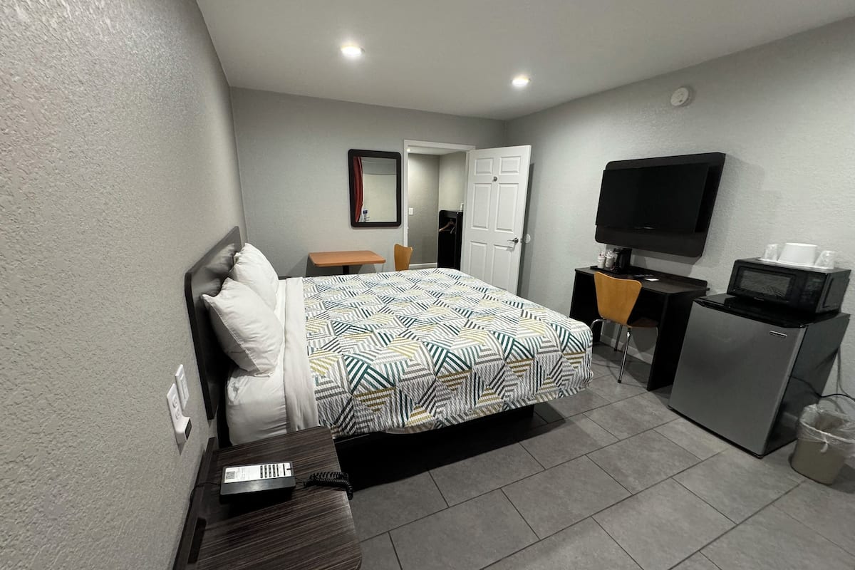 Habitación de hotel con cama, escritorio, televisor y microondas.
