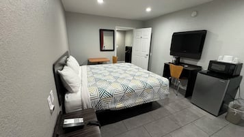 Une chambre d’hôtel équipée d’un lit, d’un bureau, d’une télévision et d’un four à micro-ondes.