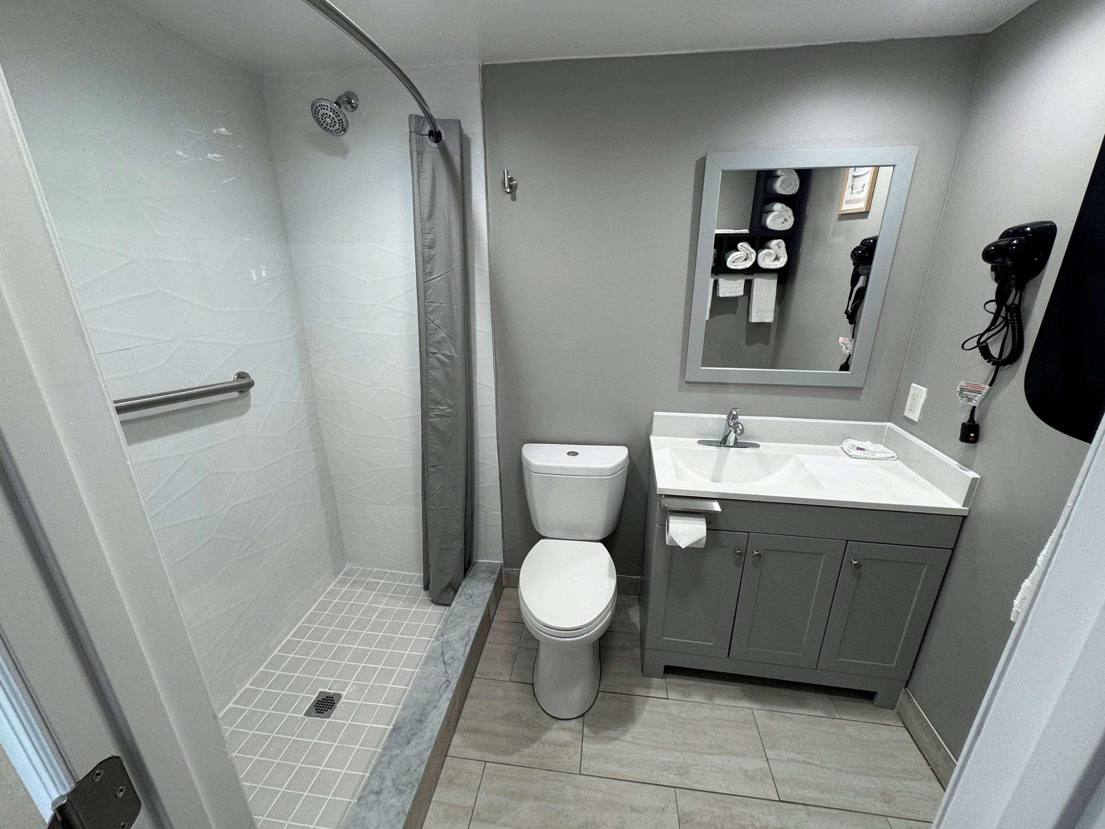 Ein modernes Badezimmer mit Dusche, Toilette, Waschbecken und Spiegel.