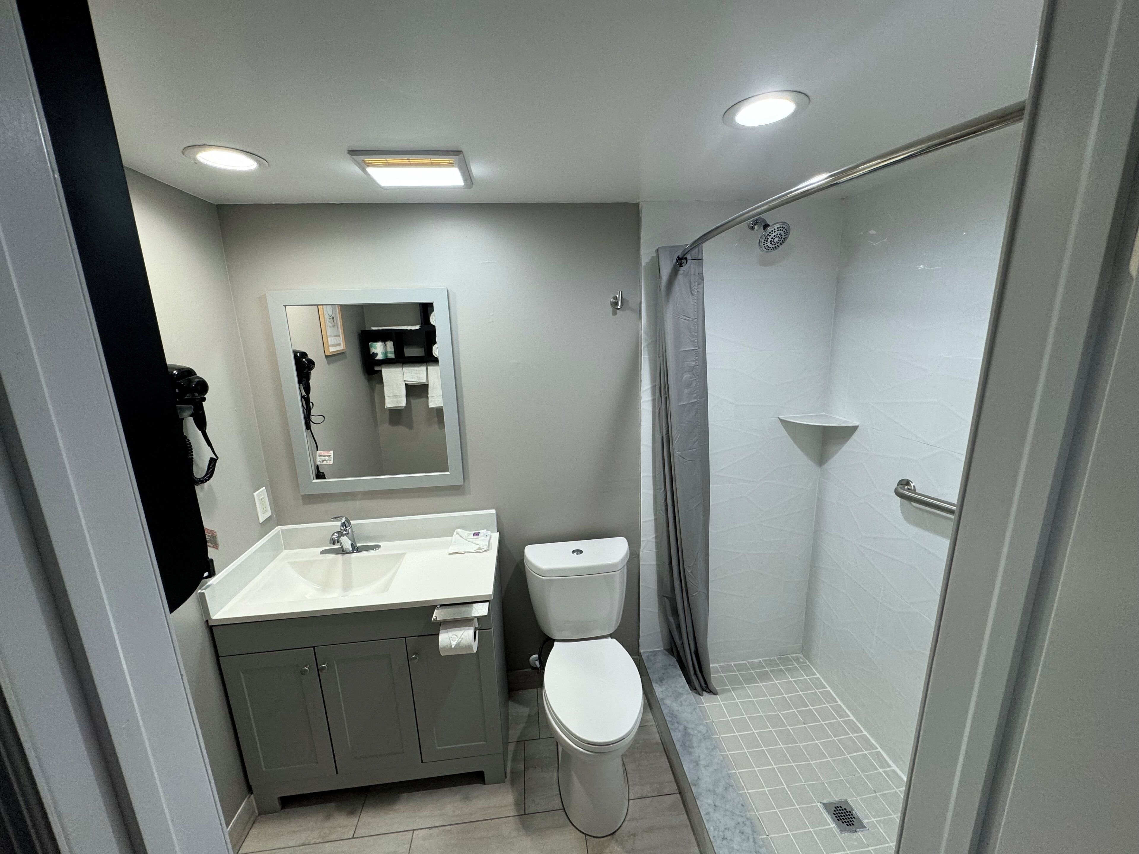 A modern bathroom with a shower, toilet, and sink.