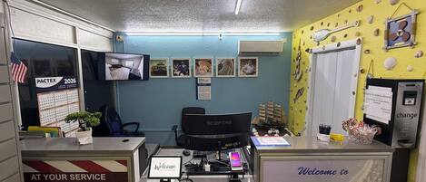 A reception desk with a 'Welcome to ENGLEWOOD' sign, a computer, and a 'PACTEX 2026' calendar.