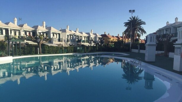 Una piscina rodeada de edificios modernos bajo un cielo azul despejado.