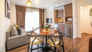 A modern living room with a sofa, dining table, and chairs. There is a kitchen area with a microwave and refrigerator. - Ebe1par1133- Apartment in Avenida Paralelo (Barcelona)
