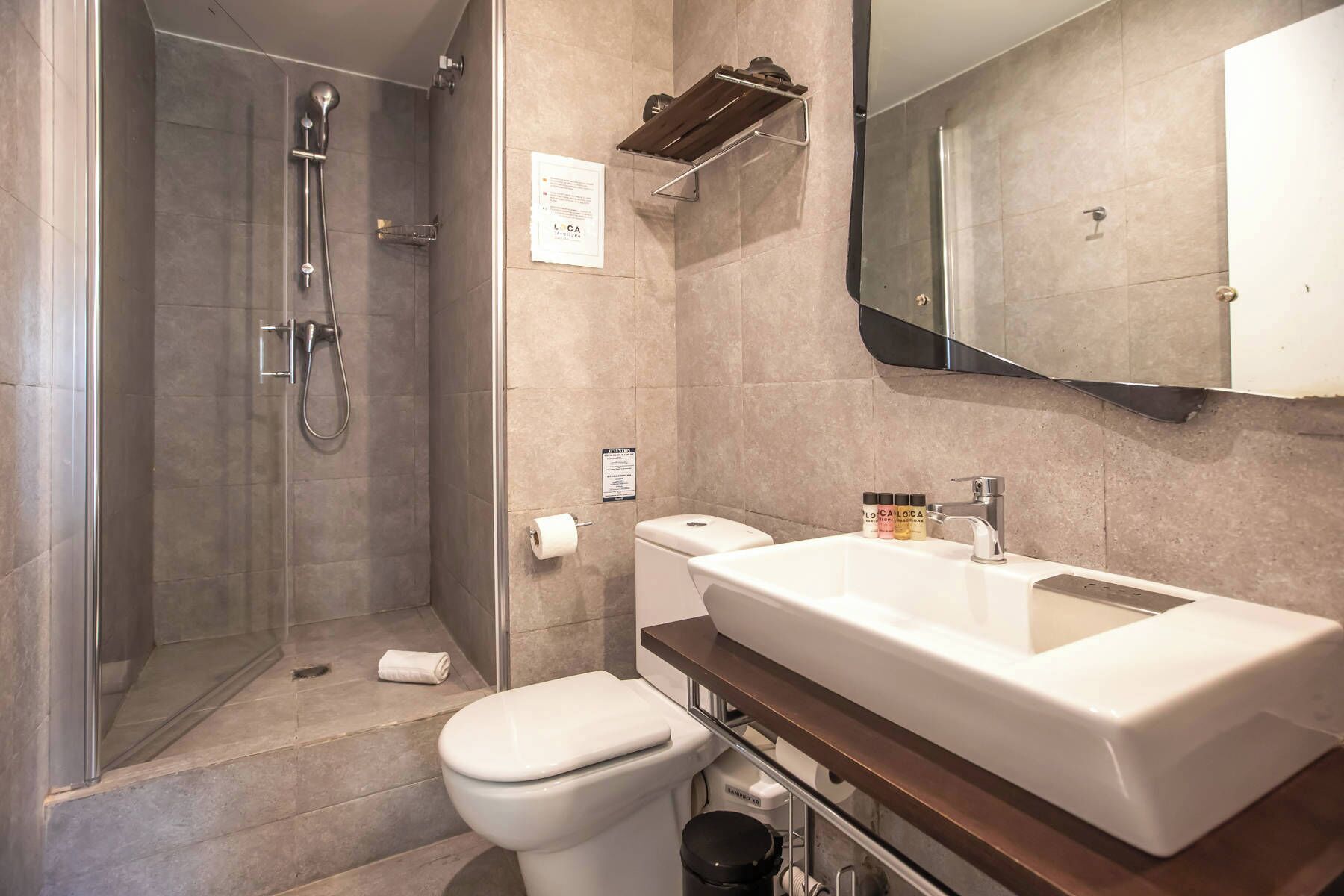 Un baño con ducha, inodoro y un lavabo grande con espejo arriba.