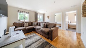 A modern living room with a sectional sofa, a flat-screen TV, and a large window with curtains. - Paddington Lodge (Brigg)