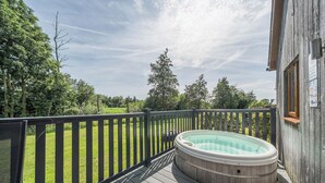 A wooden deck with a hot tub, surrounded by a wooden fence and trees. - Paddington Lodge (Brigg)