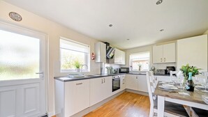 Eine moderne Küche mit weißen Schränken, einem eingebauten Backofen und einem Essbereich mit Holztisch und Stühlen.