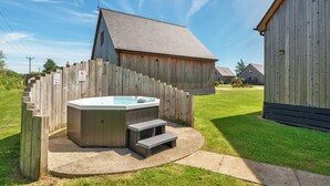 Ein Holz-Hottub mit Stufen, ein Holzzaun und ein bauerndienstliches Gebäude auf einer Wiese.