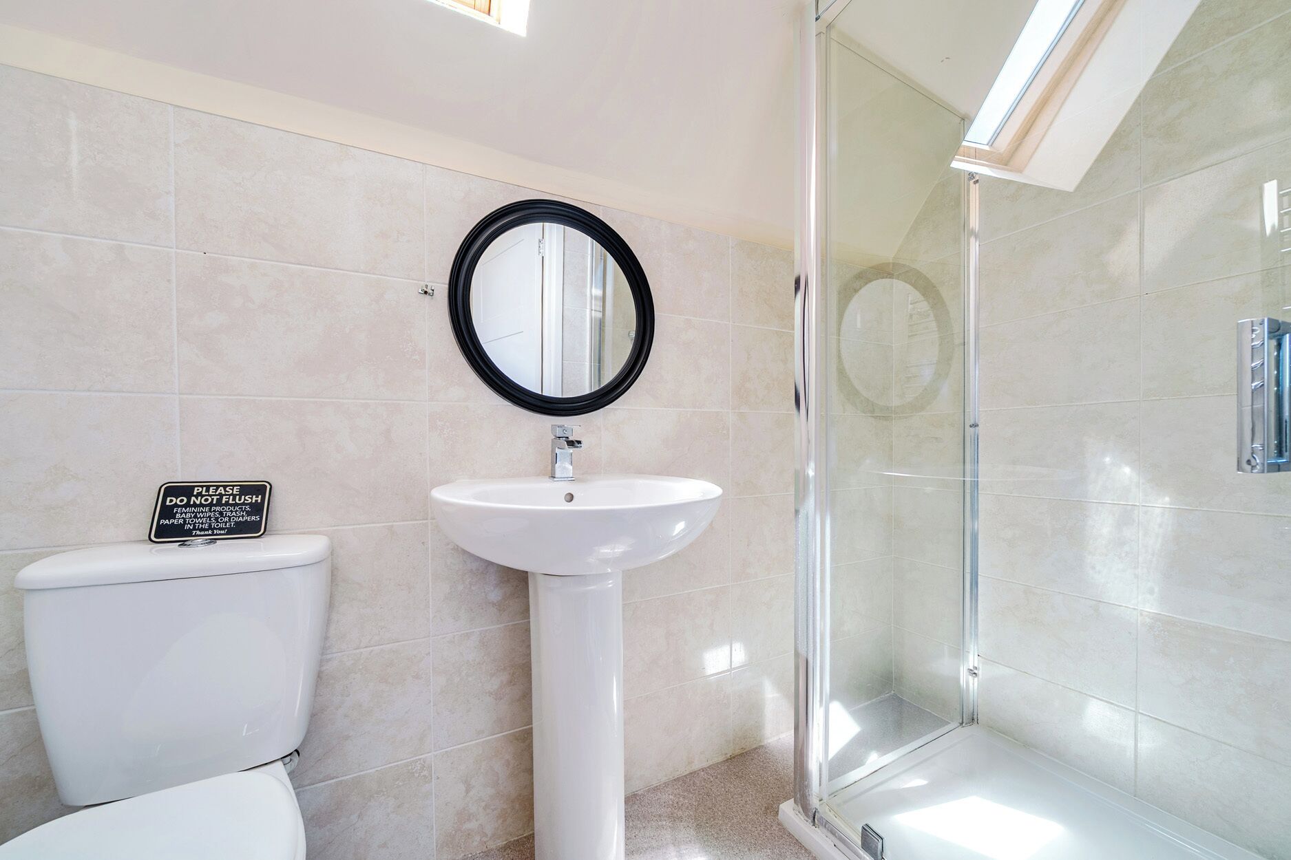 A bathroom with a toilet, sink, and glass shower enclosure.