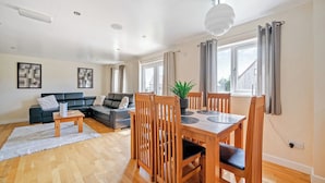 A modern living room with a sofa, dining table, chairs, and a potted plant. - Lodge 2 - Charcoal (Brigg)