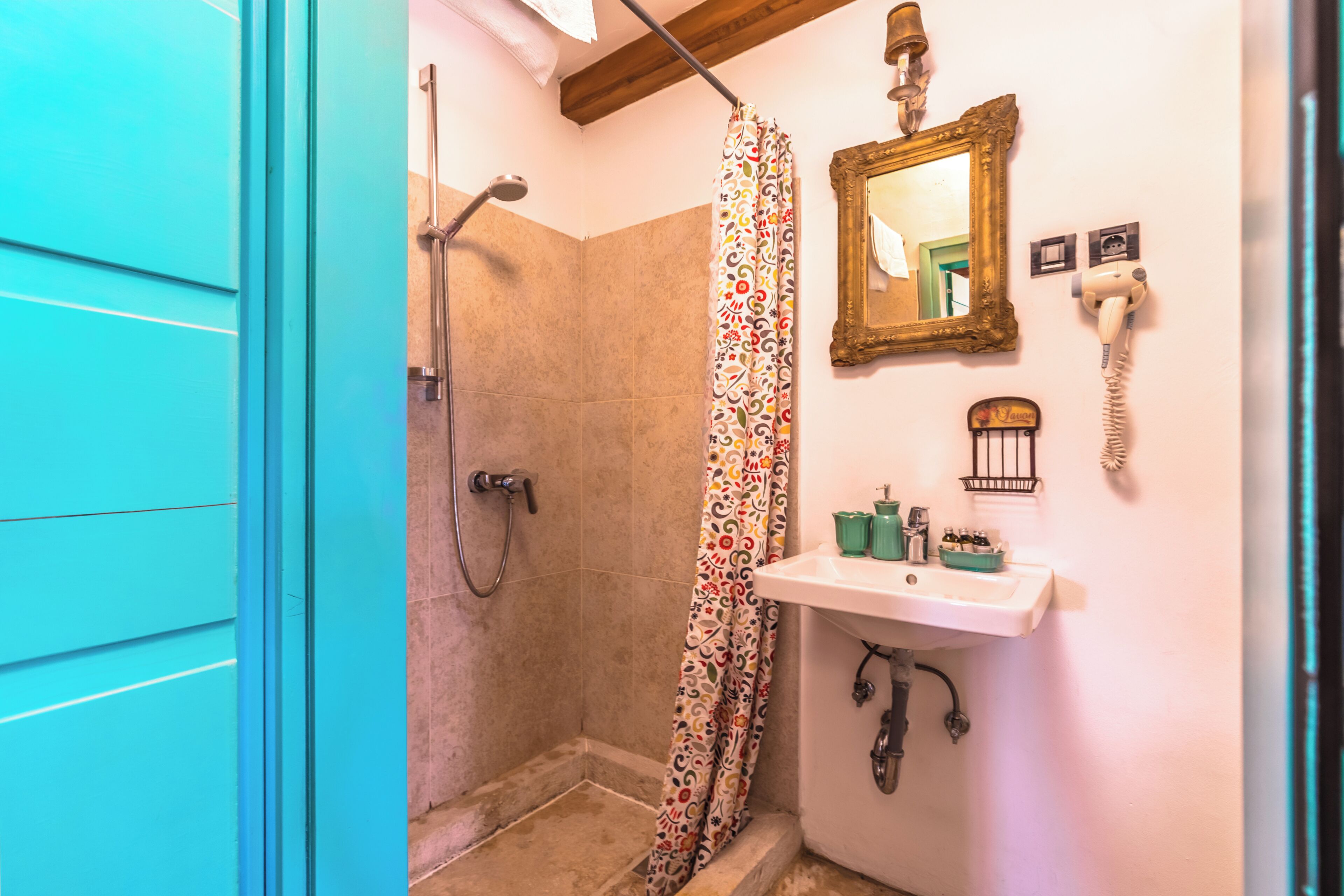A bathroom with a shower, a sink, a mirror, and a telephone.