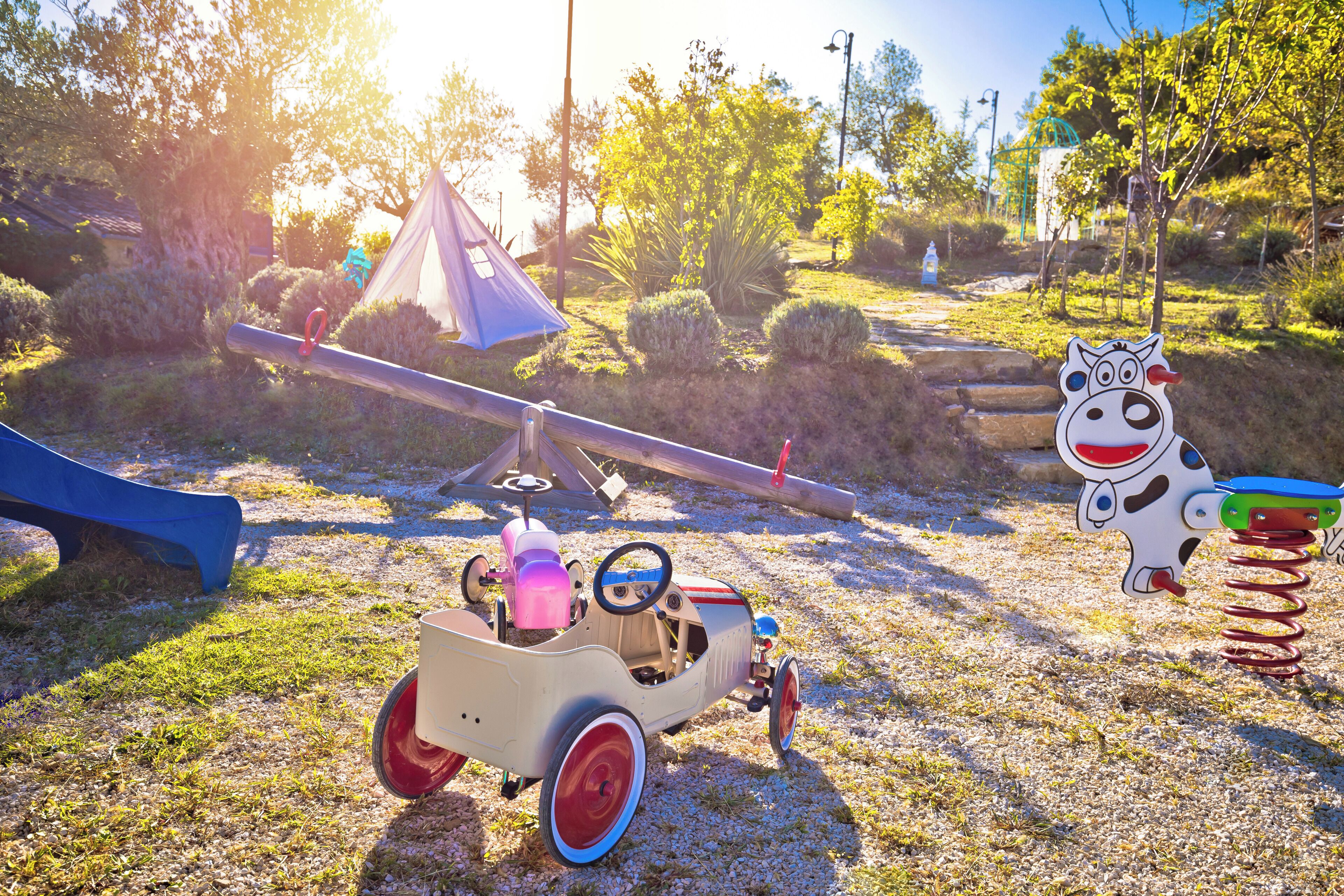 A playground with a seesaw, a toy car, and a cow-shaped swing set.