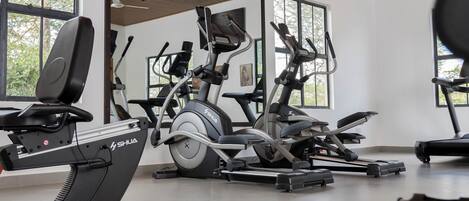 A gym with stationary bikes, elliptical machines, and a treadmill.