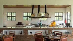 Een ruime keuken met grote ramen, een bakstenen aanrecht en een kok die kookt.