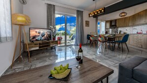 Un salon moderne comprenant un téléviseur, un coin repas et une cuisine.