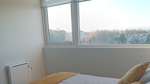 A bedroom with a bed, a window, and a radiator. - Kasa y Familia 811 (Valdivia)