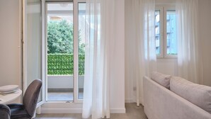 A modern living room with a sofa, a dining table, and a sliding glass door leading to a balcony. - Point of Life 1 by Litto (Split)