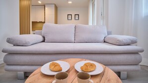 A modern living room with a light grey sofa, two plates with croissants, and two mugs on a wooden table. - Point of Life 1 by Litto (Split)