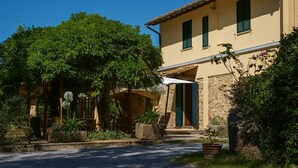 A traditional Mediterranean-style building with a stone facade, green shutters, and a covered porch with potted plants. - Podere la Botte Pool Lari (Lari)