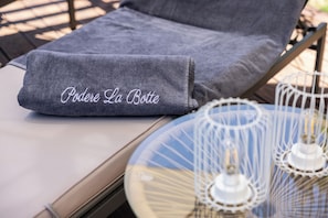 A lounge chair with a grey towel and a decorative tray with candles. - Podere la Botte Pool Lari (Lari)