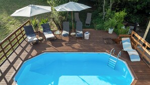 A wooden deck with a swimming pool, lounge chairs, and umbrellas. - Podere la Botte Pool Lari (Lari)