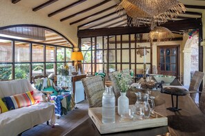 Een rustiek interieur met een houten tafel, rieten meubels en een groot raam.
