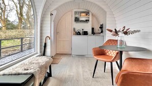 A modern interior with a large arched doorway leading to a kitchen, a dining area with a table and chairs, and a view of the outdoors. - Whole Coastal Estate · Sleeps 12 · Anglesey (Isle of Anglesey)