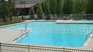 Piscina com água azul cristalina, cercada por grades e árvores.