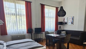 A hotel room with a bed, a desk, a chair, a sofa, and a dining table. - Bright Studio Apartment in Konstanz (Konstanz)